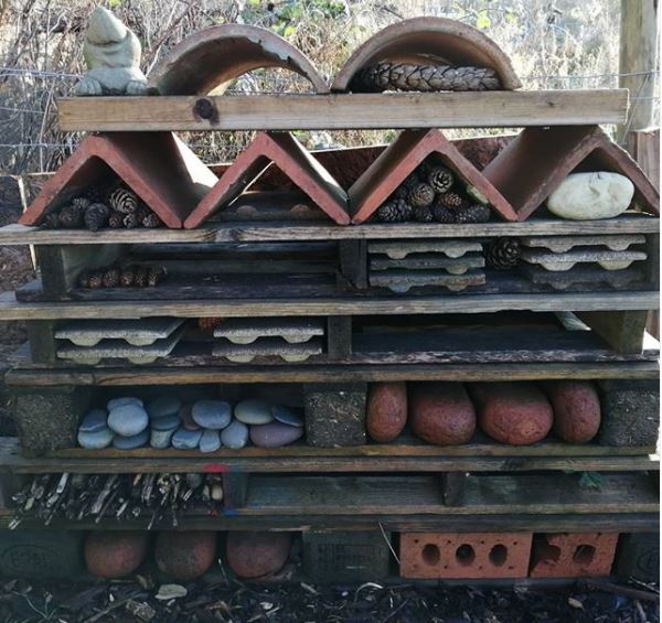 pallets, bricks, stones and clay tiles have been arranged into a large bug hotel