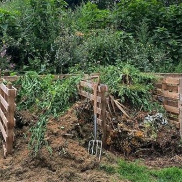 pitchfork leaning against two large open compost containers