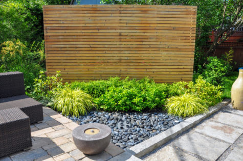 a stylish wooden screen cuts across the corner of a garden so bins can be stored behind it