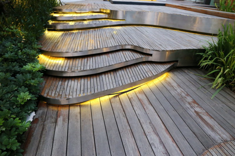 a set of wide wooden decking steps, with LED light cables hidden between the risers