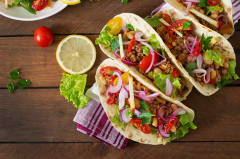 three tacos filled with tomatoes, onion, lettuce and fresh chillies