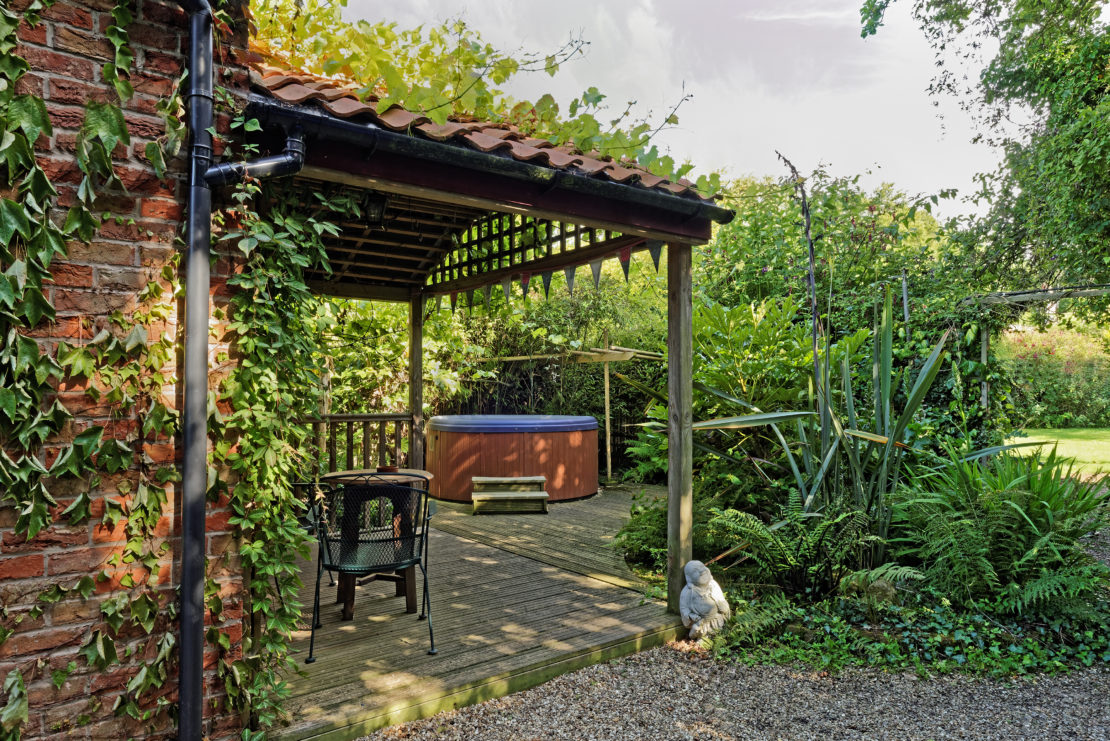 an old brick house with a wooden hot tub on a covered patio