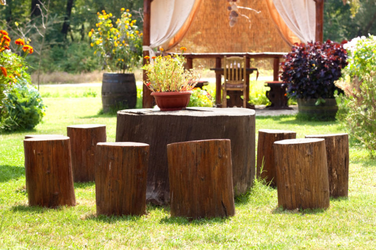 several seats made from tree stumps are sat around a larger tree stump, used as a table