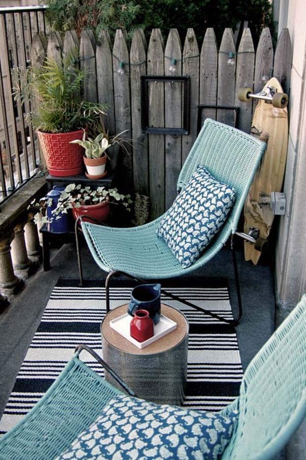 two blue wicker chairs with blue pattered cushions, contrasted with bright red plant pots