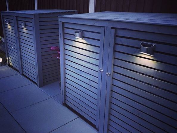 Bin Storage Ideas: How to Hide Your Wheelie Bins and Conceal Your Compost 8 two modern bin sheds made from wood panels painted grey, with stylish metal handles that have a light fitted to them