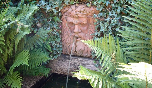 14 Stunning Garden Water Feature Ideas: Finding a Fountain for Your Home 5 a terracotta wall fountain in the shape of a face with water spouting from its mouth