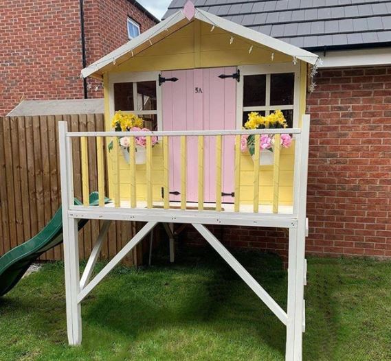 a raised playhouse with a slide coming down one side