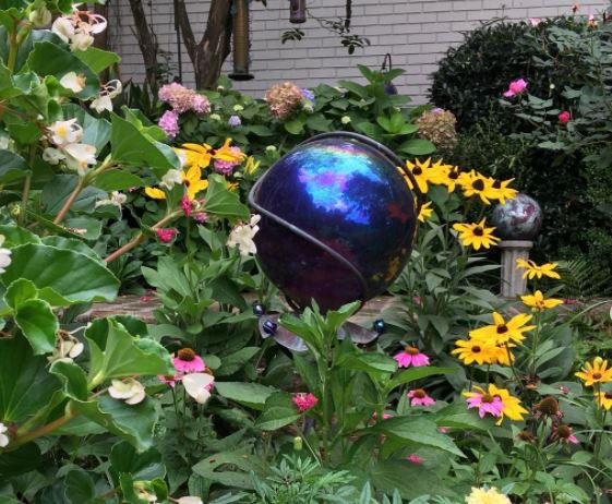 a dark blue orb makes an enchanting garden sculpture