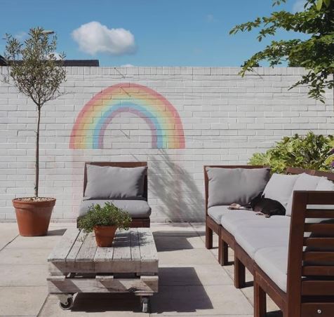 garden play area ideas with a plain grey wall painted with a chalk rainbow