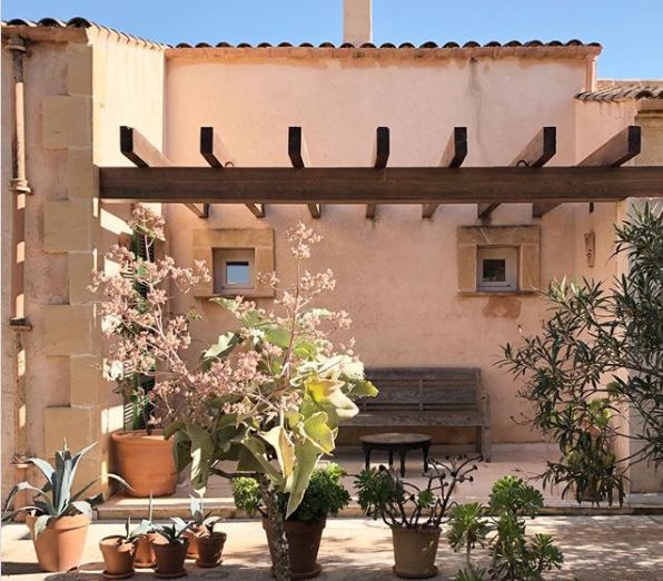 Spanish Themed Garden Ideas: Turn Your Garden into a Sizzling Iberian Sanctuary 10 a peach stucco building with a pergola-covered patio and potted plants
