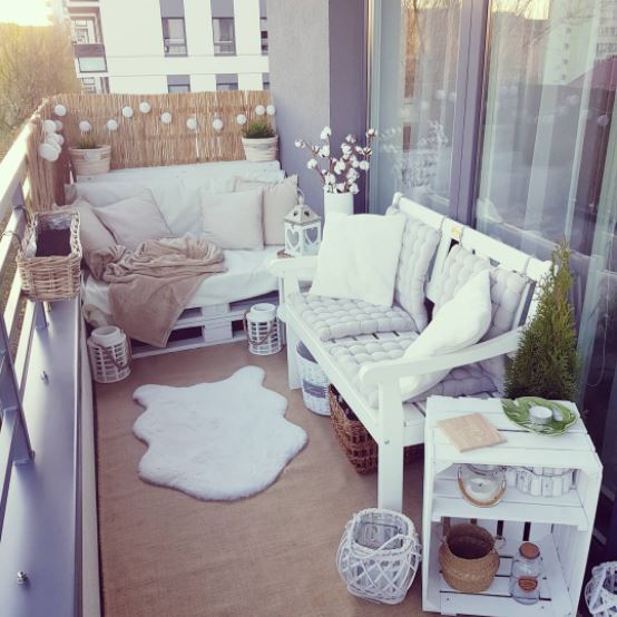 a small, cosy balcony with pallet seating and fine bamboo matting to create privacy