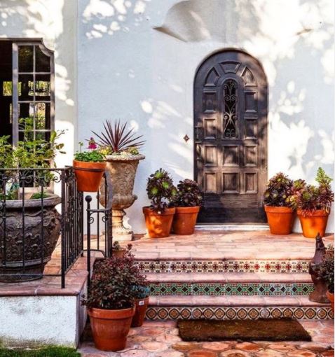 Spanish Themed Garden Ideas: Turn Your Garden into a Sizzling Iberian Sanctuary 5 an arched doorway with tiled steps and a collection of plants in terracotta pots