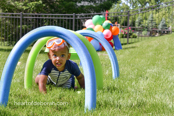 young boy crawling through pool noodle obstacles