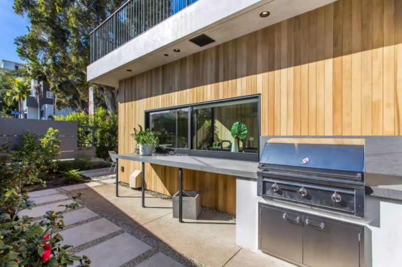 20 Garden Kitchen Ideas For The Perfect Outdoor Cooking Area 18 an outdoor kitchen along the exterior of a house, with a sliding window to the indoor kitchen