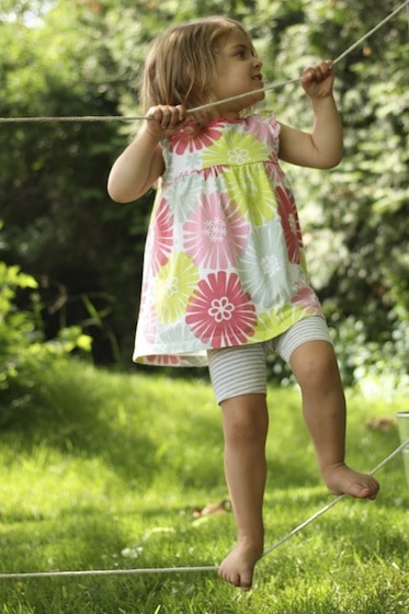 child balancing on tightrope between trees