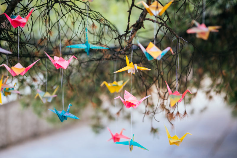 little origami paper cranes hanging from tree branches