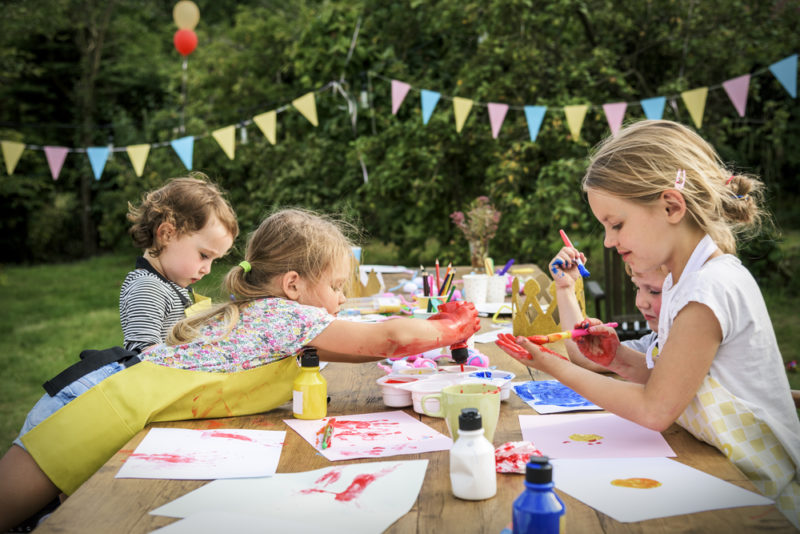 three children sit around a table amicably crafting