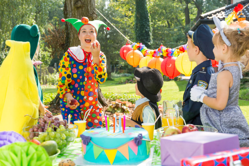 a clown juggles to entertain children in the garden