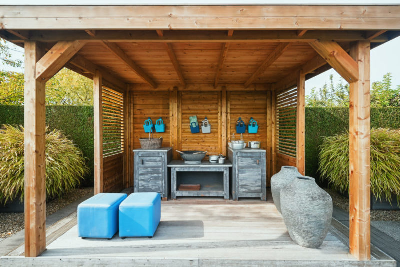 20 Garden Kitchen Ideas For The Perfect Outdoor Cooking Area 21 a gazebo with rustic wooden kitchen units and blue cushioned benches