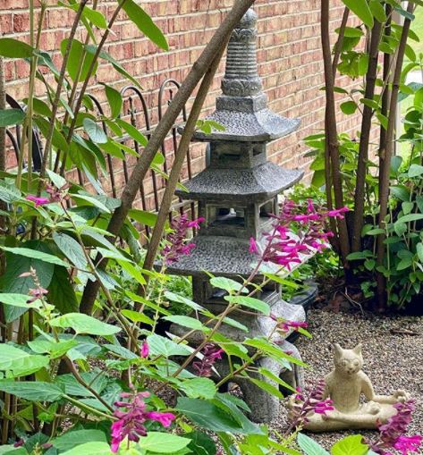 a stone lantern next to a leafy flower bed