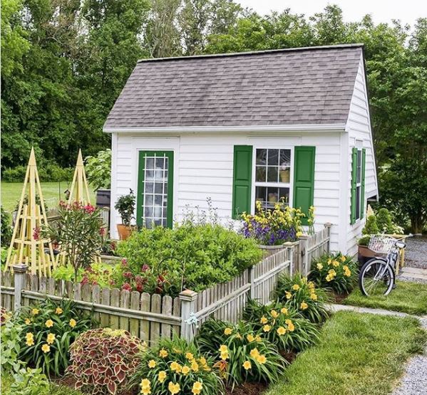 40 Garden Shed Ideas for Pretty to Practical Outdoor Buildings 13 a white shed with green shutters around the windows and a green door