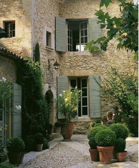 exterior of a house with sage green shutters and warm, sandy coloured bricks and gravel
