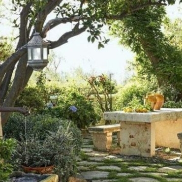 Italian style garden ideas with mossy paving stones, stone bench, water fountain and orange trees