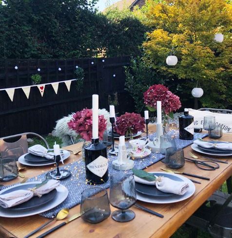 a wooden patio table with floral centrepieces and beautiful table settings