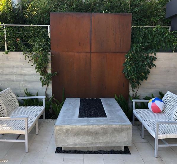 a sculptural fire pit with rust coloured metal backdrop