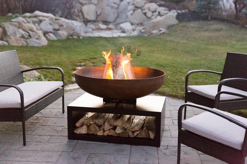a metal garden fire bowl with log storage underneath