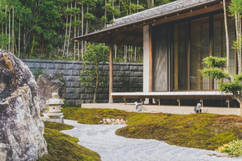 A Japanese building with a mossy garden and pebble "stream"