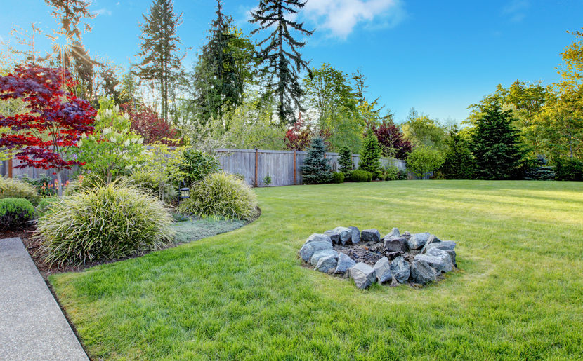 29 Garden Fire Pit Ideas for Cosy Evening Get-Togethers 16 a ring of stones with a campfire in the middle of a lawn