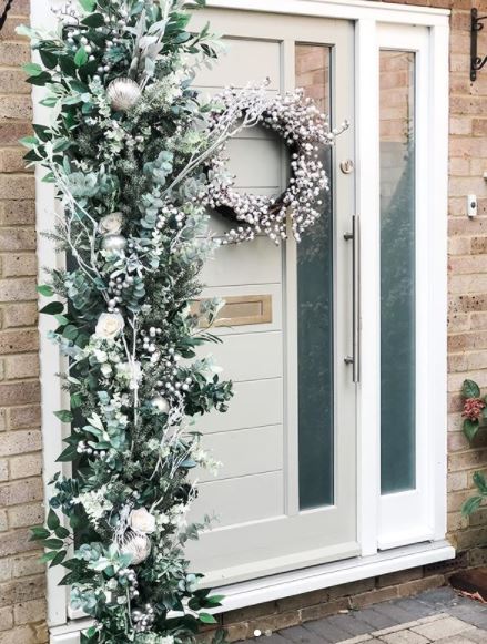 a bushy festive wreath, hanging vertically next to a front door