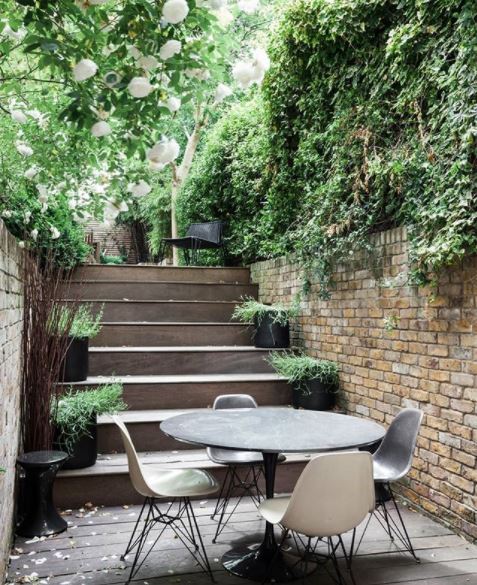 17 Long Garden Ideas to Design a Narrow Outdoor Area 9 garden steps leading down to a patio area with a dining table enclosed in greenery
