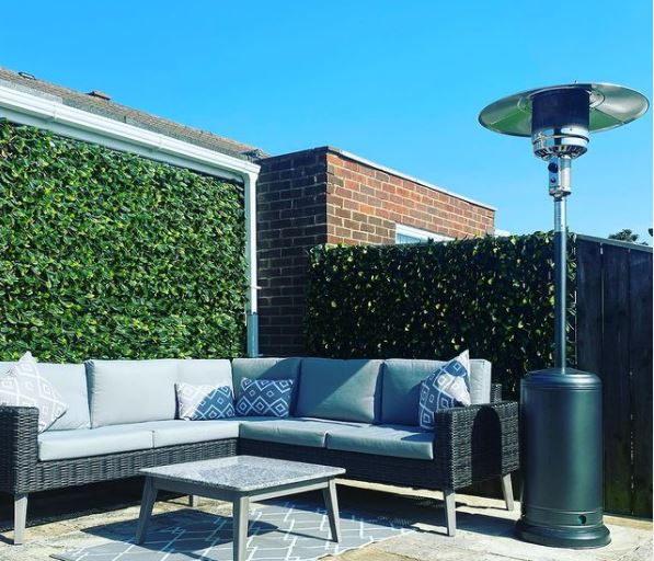 a green wall, corner sofa and gas patio heater