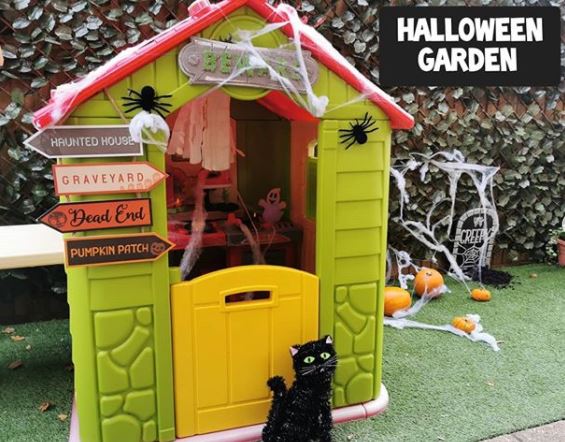 22 Halloween Garden Ideas: Fun & Low-cost Spooky Decorations 21 a toy playhouse decorated with fake cobwebs, spooky direction signs and a toy black cat