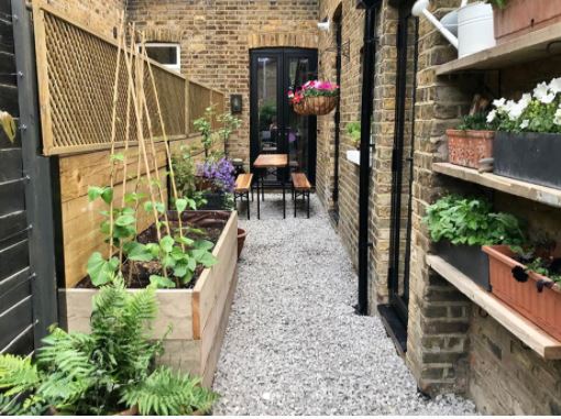 15 Grass Free Garden Ideas: Stunning Low Maintenance Yards 6 a narrow side-return garden with gravel, seating area, vegetable planter and flowers in pots on shelves