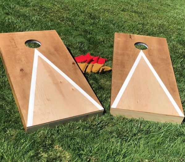 two DIY cornhole ramps on a lawn with beanbags to play the game