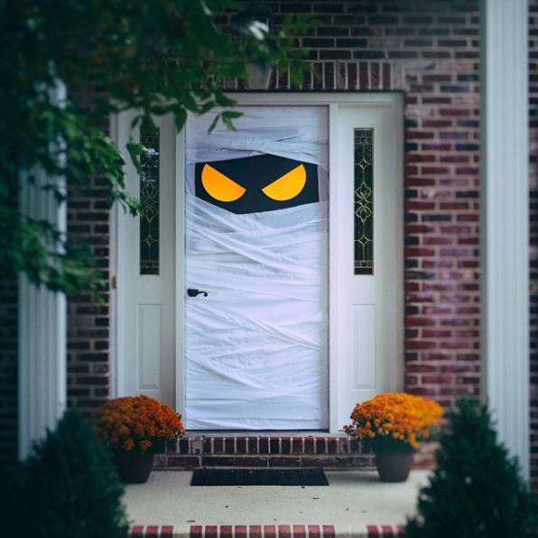 22 Halloween Garden Ideas: Fun & Low-cost Spooky Decorations 16 a front door wrapped in bandages with large stylised eyes peeping through