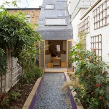 a very narrow garden with a gravel path and planters and trellises on either side