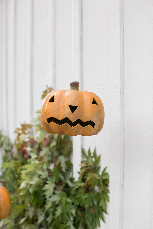22 Halloween Garden Ideas: Fun & Low-cost Spooky Decorations 15 a paper mache pumpkin hung up with fishing wire to look like it is floating
