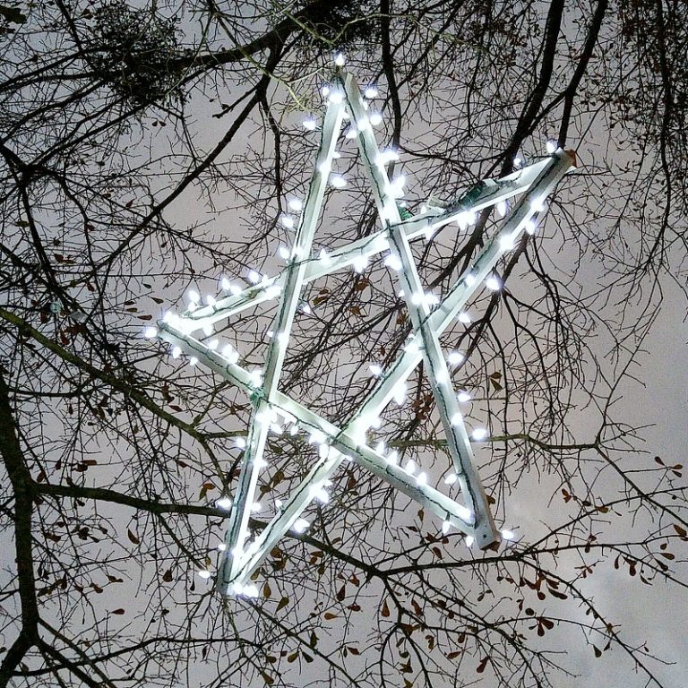 a large wooden star covered in string lights hangs in a tree