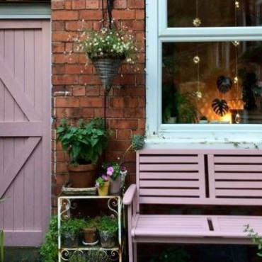 the wall of a house with a wooden bench painted pink and a side gate painted in the same colour