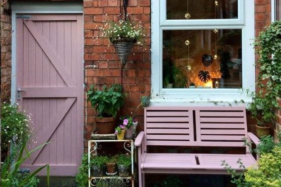 the wall of a house with a wooden bench painted pink and a side gate painted in the same colour
