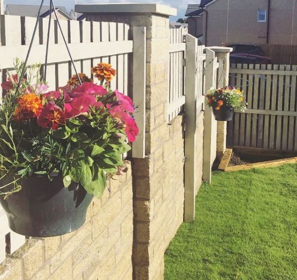 a fence with hanging baskets filled with pink and orange flowers