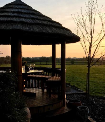 a round, tropical style gazebo made from wood with a thatched grass roof