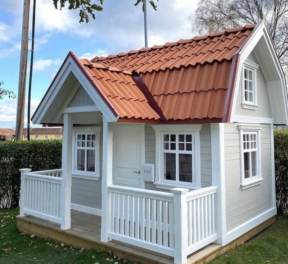 a playhouse styled to look like an american home with a red tiled roof