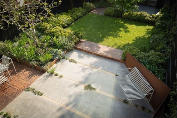 a garden with a contemporary deck and concrete patio, leading to a lawn
