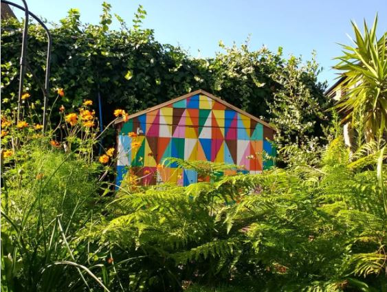 a garden shed painted with brightly coloured triangles