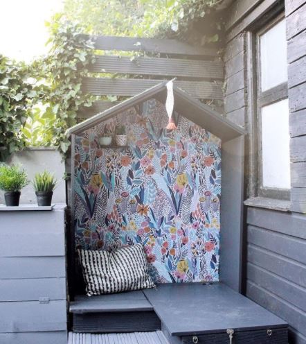 an open-faced garden playhouse with a colourfully painted back wall